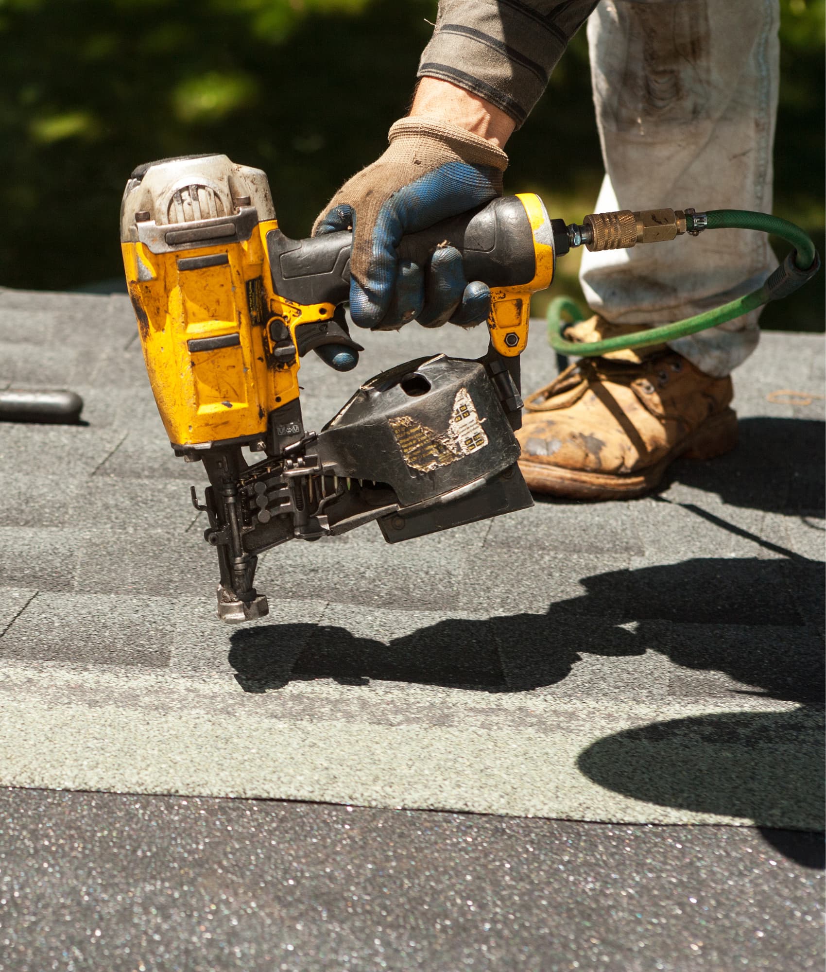 A workman carefully nailing down shingles to a roof in Saint Johns County, Florida